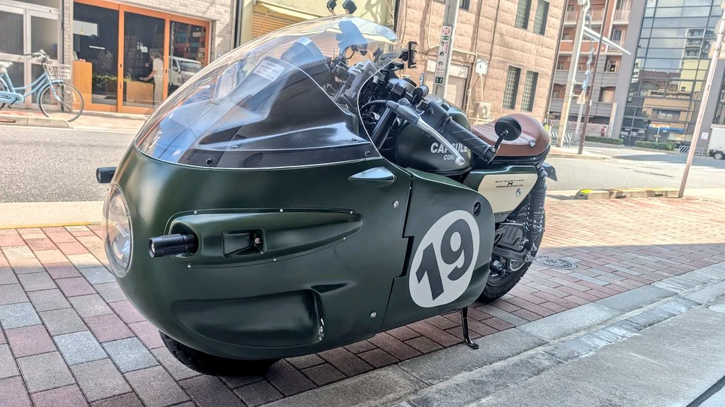 Vue rapprochée de la réplique de la moto Bulma numéro 19 avec son pare-brise plexi et le branding Capsule Corp