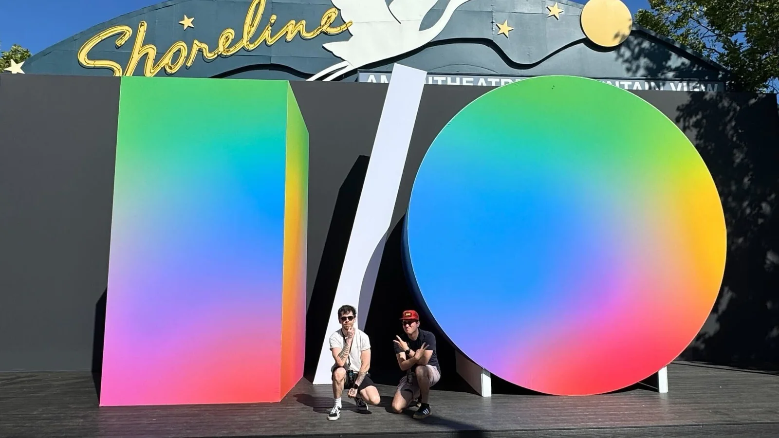 Deux participants à Google I/O 2026 prenant la pose devant le logo I/O géant aux couleurs arc-en-ciel au Shoreline Amphitheatre