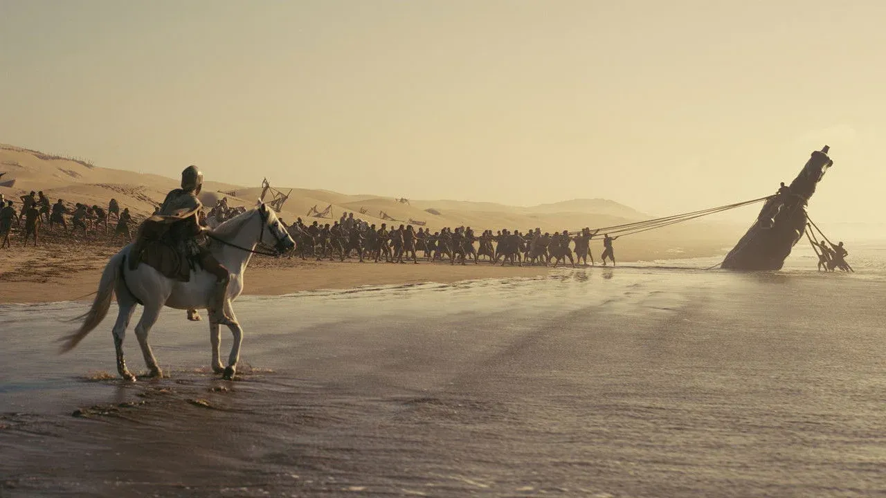Une plage à l'aube dans The Odyssey de Christopher Nolan, une armée traînant un vaisseau hors de l'eau