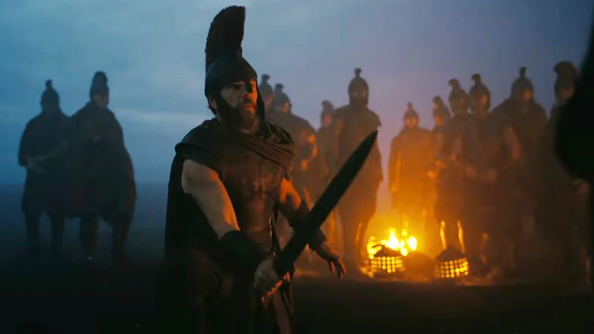 Matt Damon en Ulysse, épée à la main devant ses soldats dans la nuit, dans une scène de The Odyssey