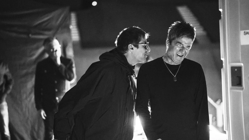 Liam et Noel Gallagher en coulisses, hilares, dans une image en noir et blanc du documentaire Oasis : Don't Look Back in Anger