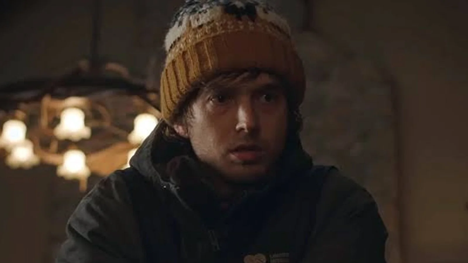 Austin Abrams en bonnet de laine jaune, le regard inquiet, dans une scène de Resident Evil