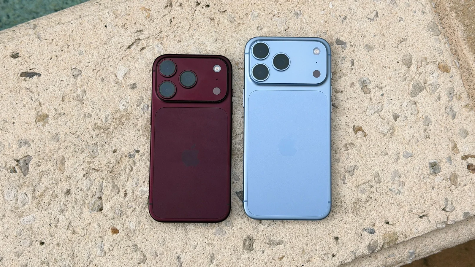 Un iPhone 18 Pro Bourgogne et un iPhone 18 Pro Max Glacier posés dos visible sur un muret en pierre
